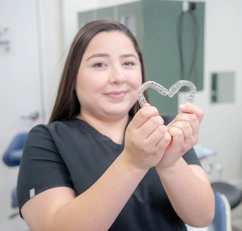 A Premier team member holding clear aligners